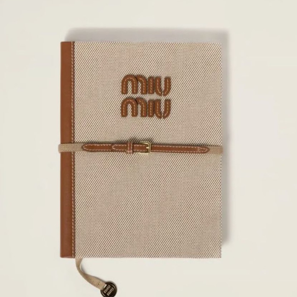 Elegant Miu Miu notebook in cream and brown. Features a sleek design.